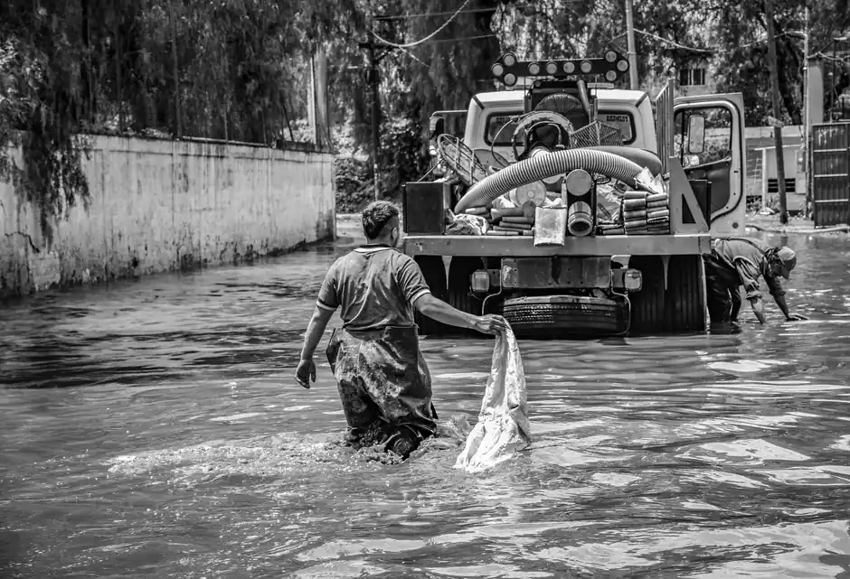 A black and white photo depicting flood cleanup efforts in an urban setting, showcasing resilience.
